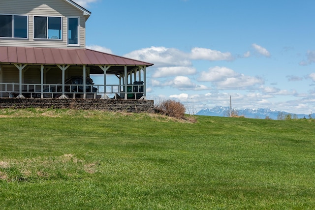 view of side of property with a lawn, a mountain view, and metal roof
