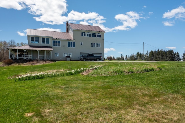rear view of house with an attached garage, a yard, and metal roof