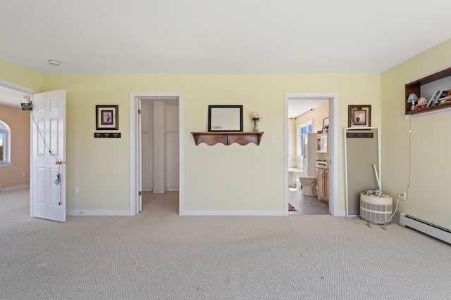 interior space with baseboards, a baseboard radiator, a walk in closet, and multiple windows