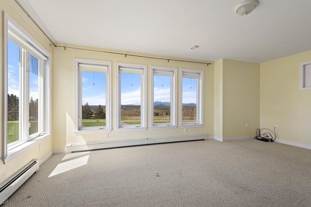 carpeted empty room featuring baseboards, baseboard heating, and a healthy amount of sunlight