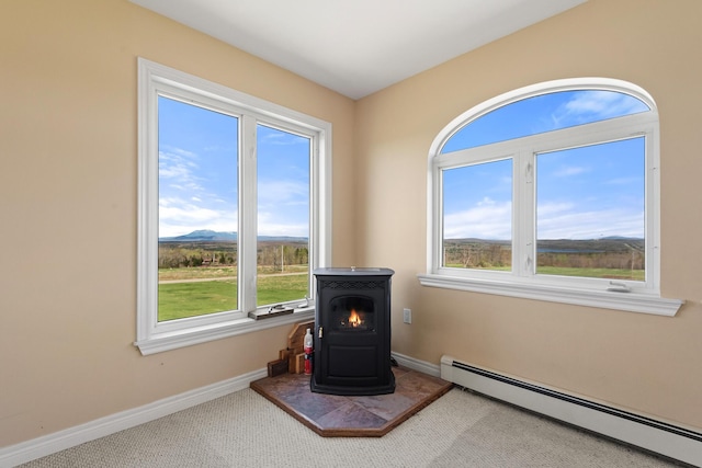 room details featuring carpet flooring, a wood stove, baseboards, a baseboard heating unit, and a mountain view