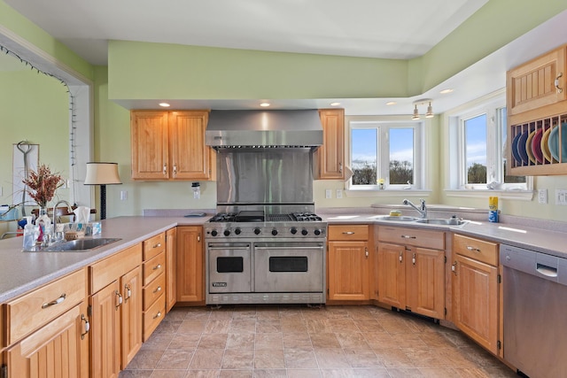 kitchen featuring a sink, appliances with stainless steel finishes, wall chimney range hood, and light countertops