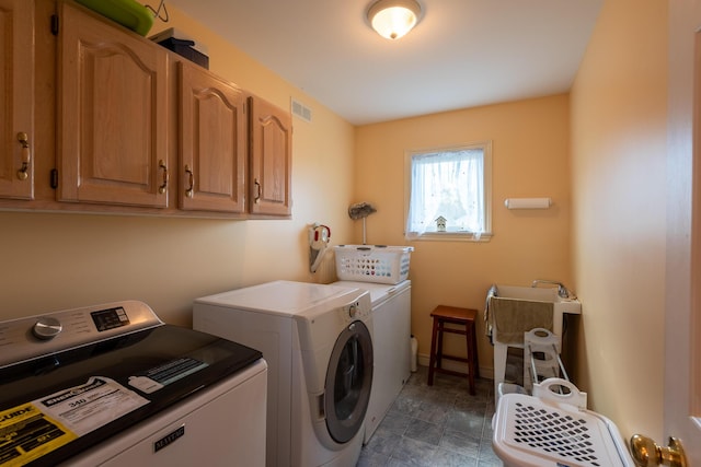 clothes washing area featuring separate washer and dryer, cabinet space, and visible vents