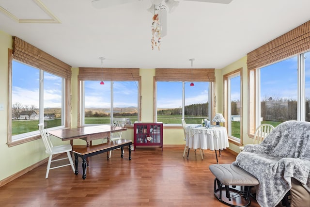 sunroom with baseboards, plenty of natural light, and wood finished floors