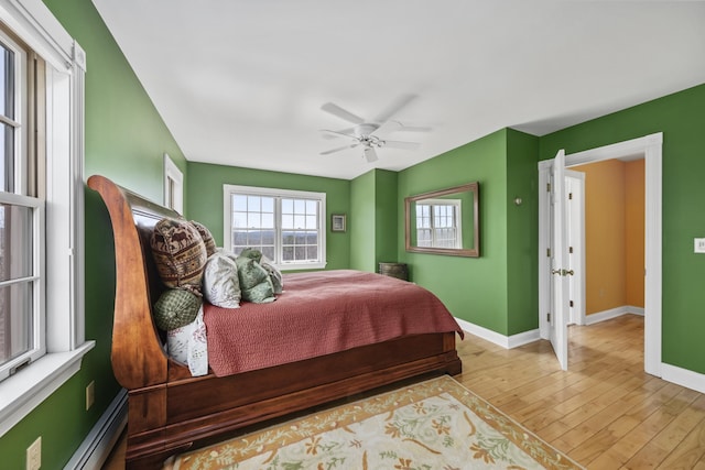 bedroom featuring baseboards, baseboard heating, ceiling fan, and wood finished floors