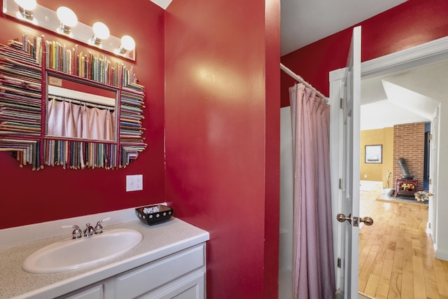 full bathroom featuring a wood stove, a shower with shower curtain, wood finished floors, and vanity