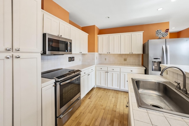 kitchen featuring white cabinetry, light countertops, appliances with stainless steel finishes, and a sink