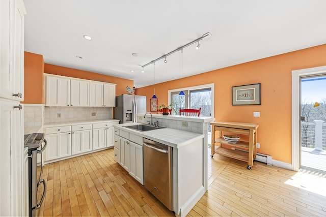 kitchen with a sink, light wood finished floors, light countertops, and appliances with stainless steel finishes