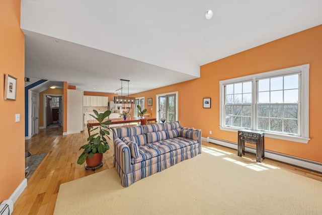 living room featuring light wood-style flooring, baseboards, a baseboard heating unit, vaulted ceiling, and recessed lighting