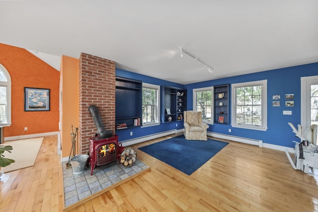 living area featuring a wood stove, hardwood / wood-style floors, and a baseboard heating unit