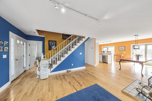 foyer entrance featuring rail lighting, stairway, and hardwood / wood-style flooring