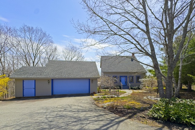 view of front of home with roof with shingles, a chimney, and a garage