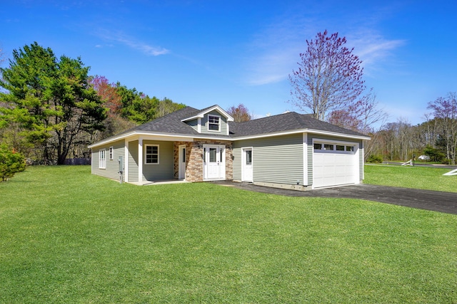 view of front facade with roof with shingles, an attached garage, stone siding, a front yard, and driveway