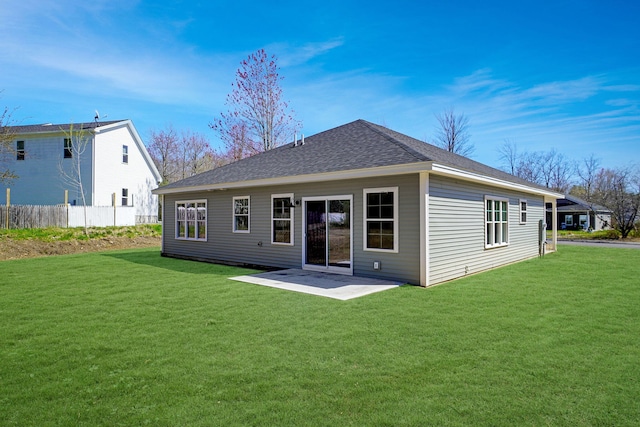 rear view of property with a lawn, roof with shingles, fence, and a patio