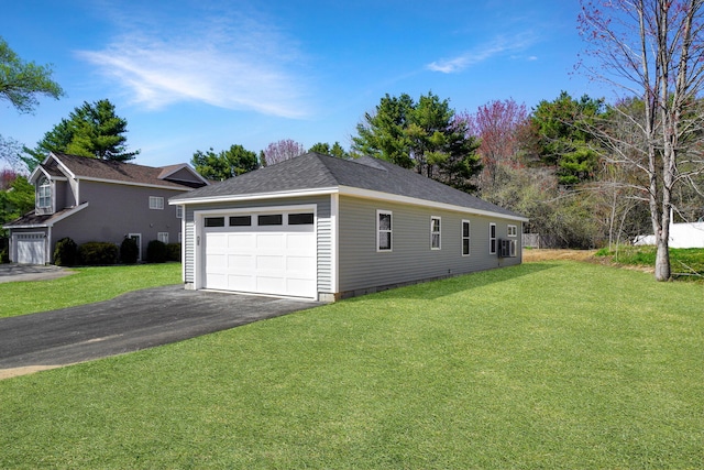 view of home's exterior with a yard, aphalt driveway, an outbuilding, and a detached garage