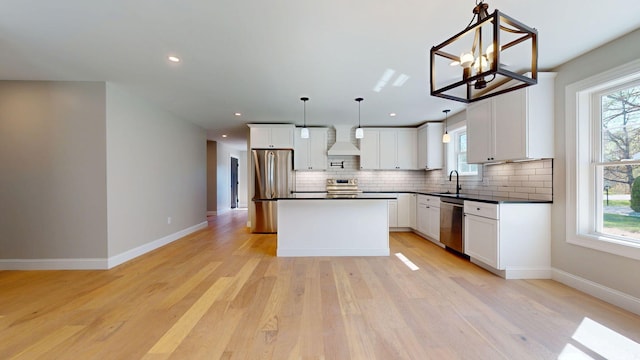 kitchen featuring wall chimney range hood, dark countertops, a sink, stainless steel appliances, and tasteful backsplash