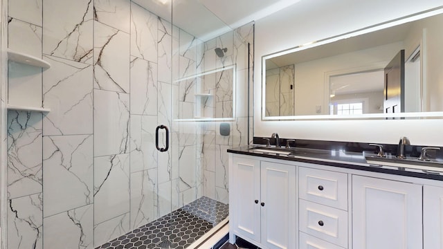 full bathroom featuring a sink, a marble finish shower, and double vanity