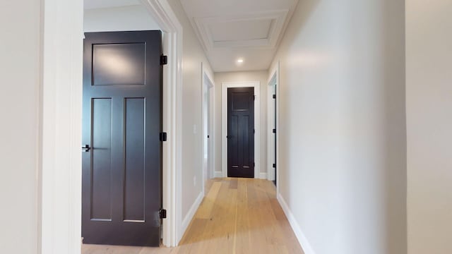 hall with light wood-style floors, baseboards, and attic access