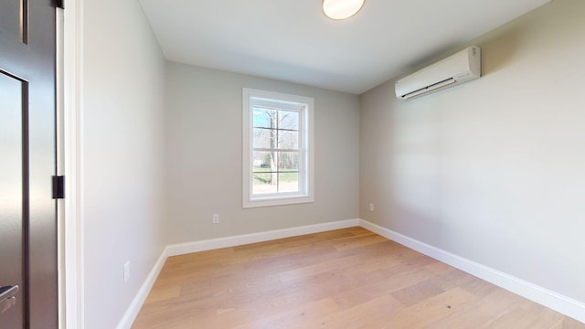 unfurnished room featuring light wood-style floors, baseboards, and a wall mounted AC