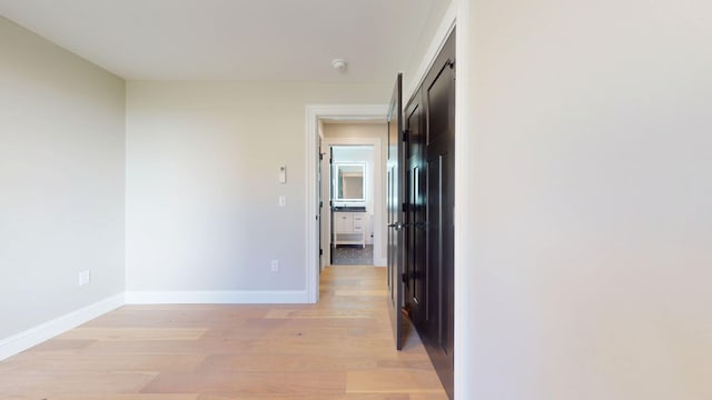 corridor featuring baseboards and light wood-type flooring