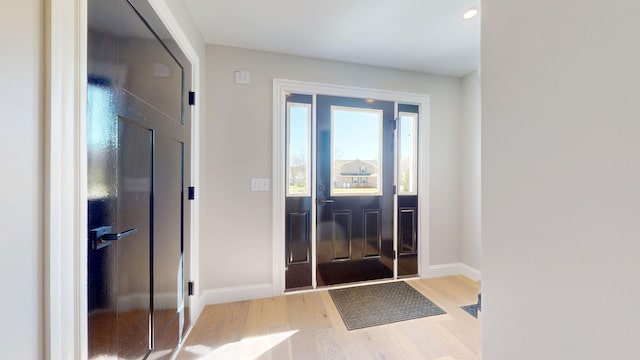 doorway to outside with baseboards and light wood-type flooring