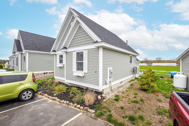 view of property exterior with roof with shingles and uncovered parking