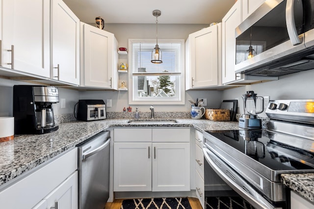 kitchen featuring white cabinetry, stainless steel appliances, light stone countertops, and a sink