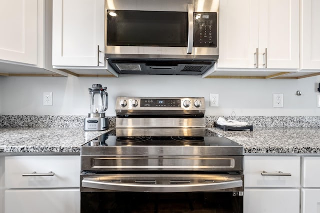 kitchen featuring white cabinets, appliances with stainless steel finishes, and light stone countertops