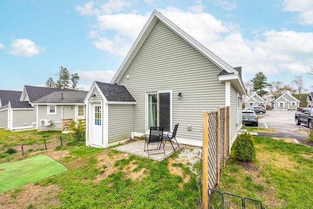 back of house featuring a lawn, a patio area, roof with shingles, and fence