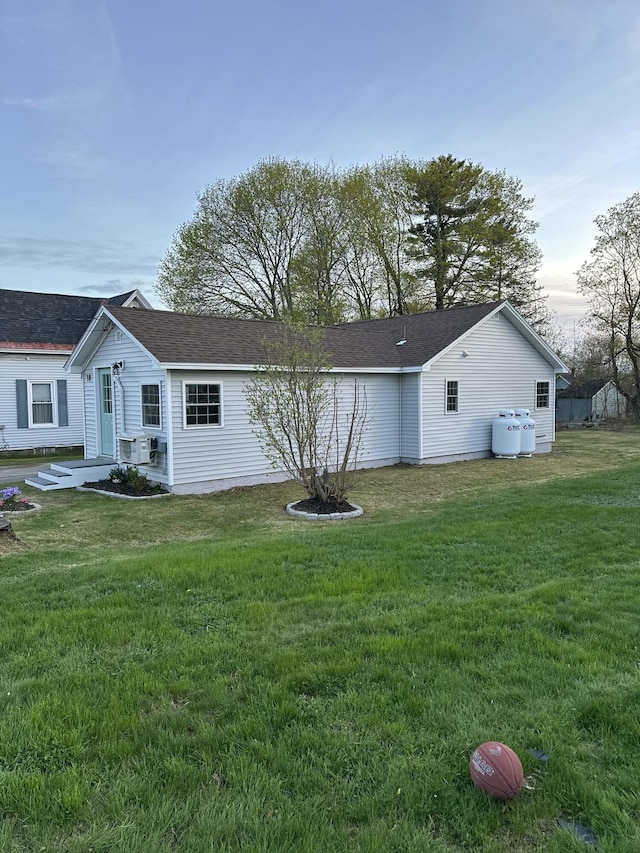 view of side of home featuring roof with shingles and a lawn