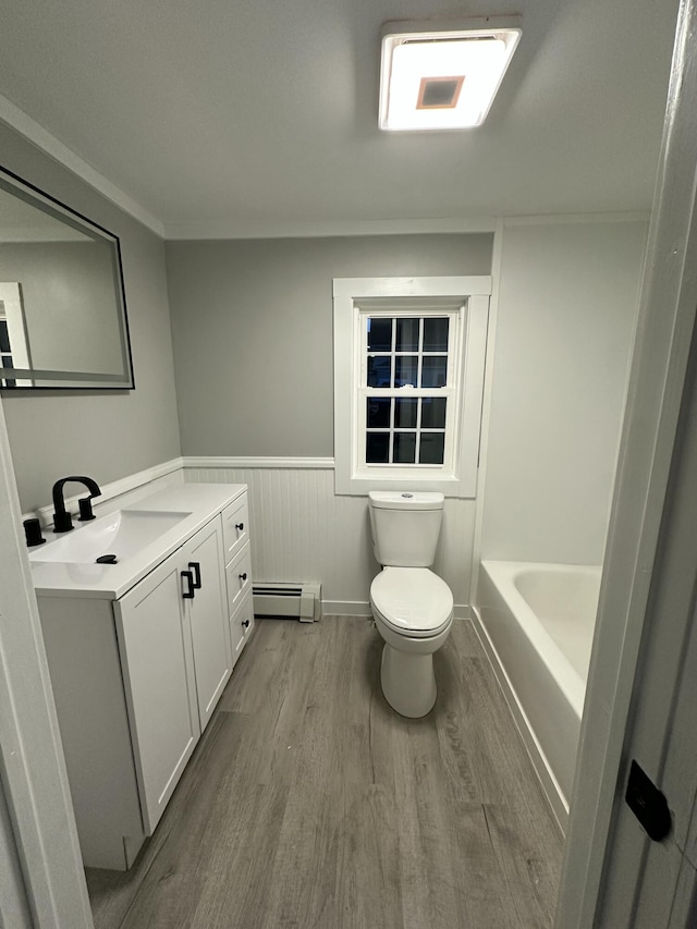 full bathroom featuring baseboard heating, toilet, a wainscoted wall, wood finished floors, and a bathing tub