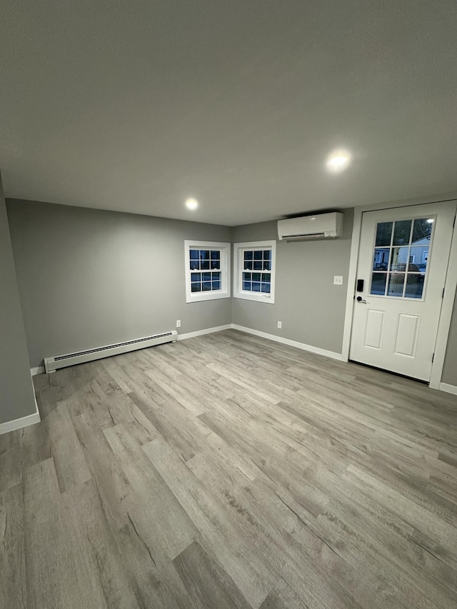 empty room featuring wood finished floors, baseboards, a baseboard heating unit, a wall mounted AC, and recessed lighting