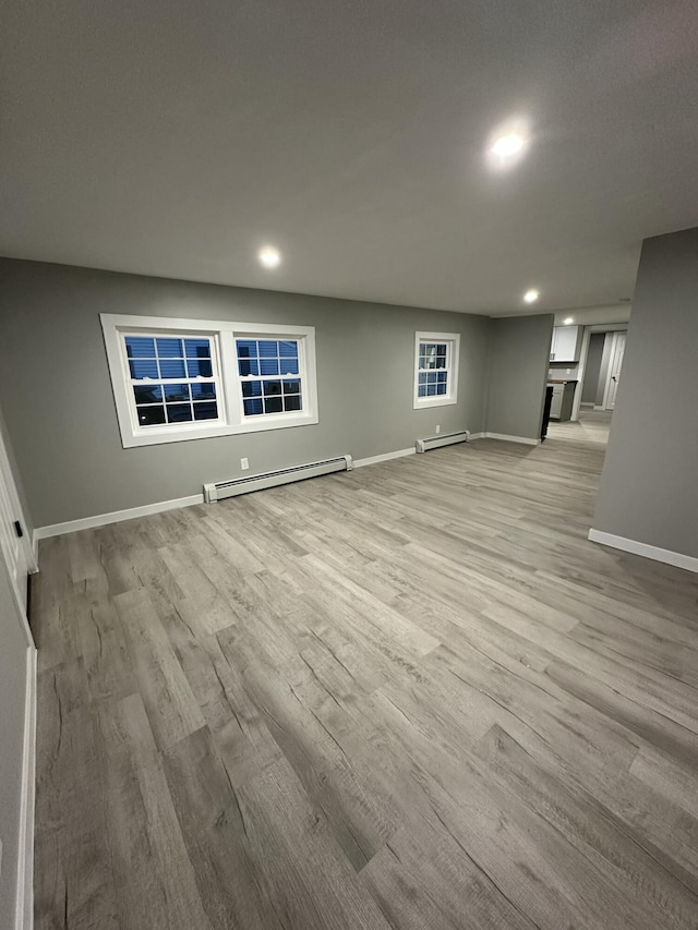 interior space with light wood-style flooring, baseboards, a baseboard heating unit, and recessed lighting