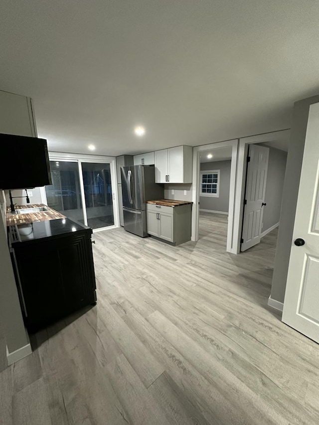 kitchen featuring freestanding refrigerator, baseboards, wooden counters, light wood finished floors, and white cabinetry