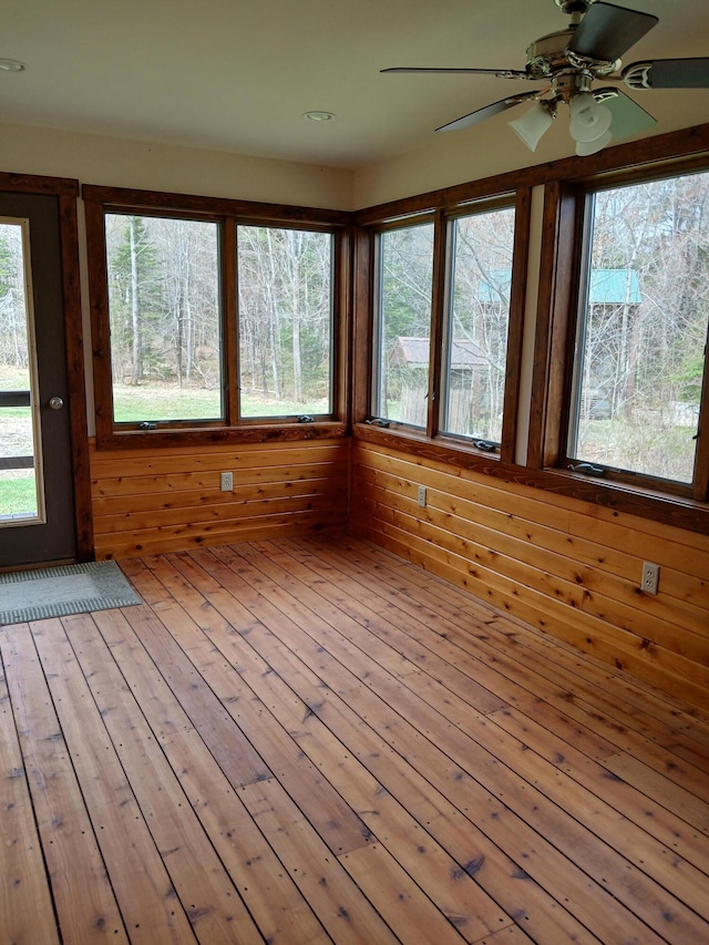unfurnished sunroom featuring wooden walls and hardwood / wood-style floors
