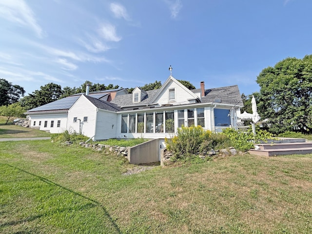 back of house with a lawn, a chimney, and a sunroom