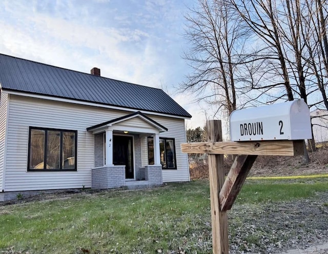 view of front of house with a chimney, a front lawn, and metal roof