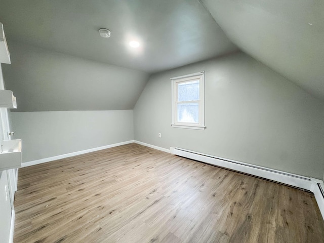 additional living space featuring baseboards, a baseboard heating unit, wood finished floors, and lofted ceiling