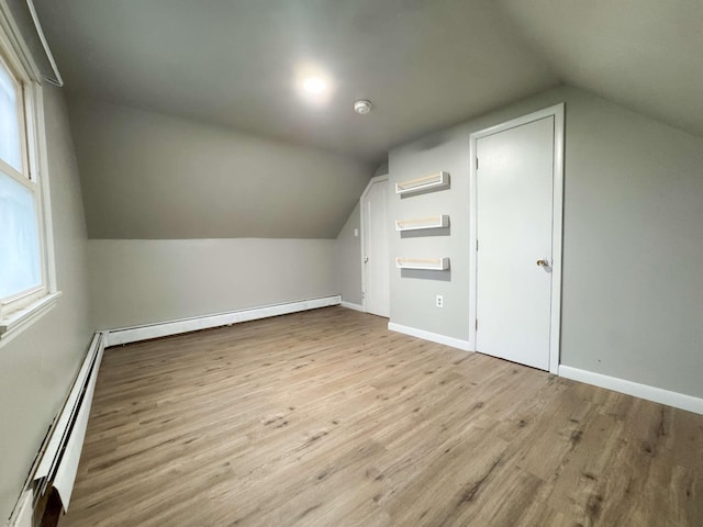 bonus room featuring baseboards, a baseboard heating unit, wood finished floors, and vaulted ceiling