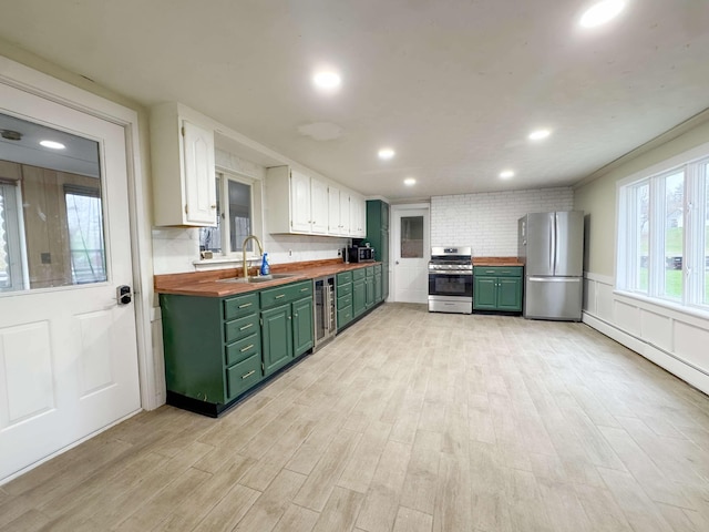 kitchen with butcher block countertops, a sink, appliances with stainless steel finishes, and green cabinets