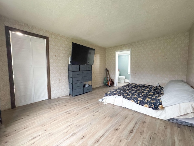 bedroom with wallpapered walls and wood finished floors