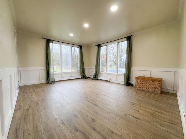 spare room with a wainscoted wall, ornamental molding, a decorative wall, and wood finished floors