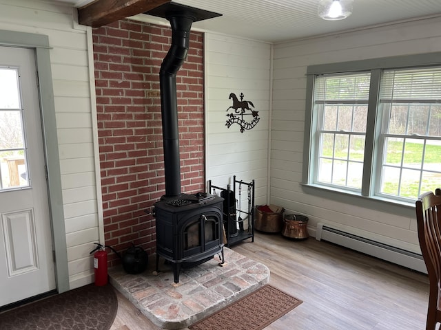 6 Gully Brook Ln, Orland, ME 04472 - detailed view of a baseboard heating unit, a wood stove, a fire extinguisher, wood finished floors, and wood walls