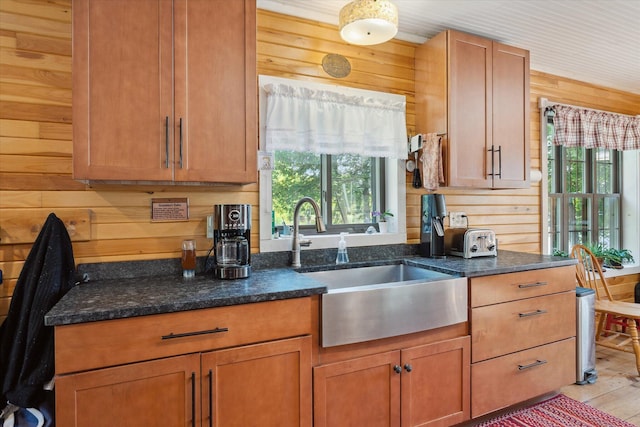 32 Whites Pond Rd, Palmyra, ME 04965 - kitchen with wooden walls, a sink, light wood-type flooring, dark stone countertops, and brown cabinets