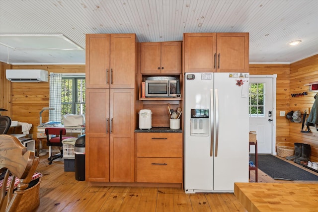 32 Whites Pond Rd, Palmyra, ME 04965 - kitchen featuring white refrigerator with ice dispenser, stainless steel microwave, a wall unit AC, healthy amount of natural light, and wood walls