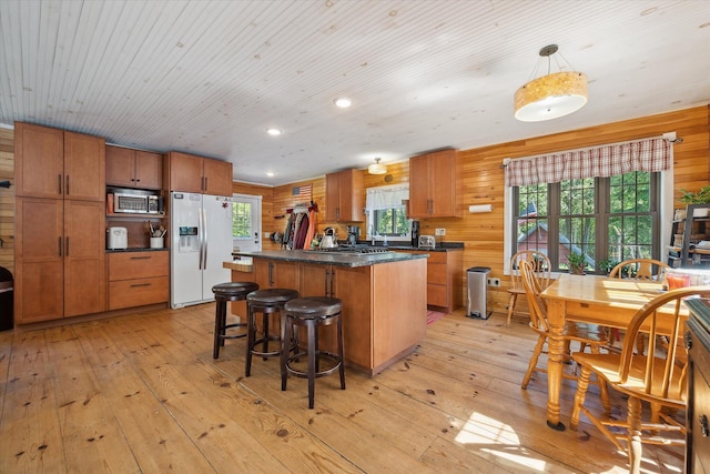 32 Whites Pond Rd, Palmyra, ME 04965 - kitchen featuring fridge with ice dispenser, stainless steel microwave, dark countertops, light wood-type flooring, and a center island