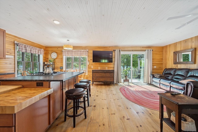 32 Whites Pond Rd, Palmyra, ME 04965 - kitchen with butcher block counters, a breakfast bar area, light wood-style flooring, wooden walls, and open floor plan