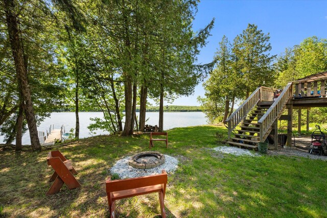 32 Whites Pond Rd, Palmyra, ME 04965 - view of green lawn featuring an outdoor fire pit, stairs, and a deck with water view