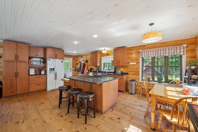 32 Whites Pond Rd, Palmyra, ME 04965 - kitchen featuring appliances with stainless steel finishes, light wood-type flooring, a kitchen island, wood walls, and brown cabinetry