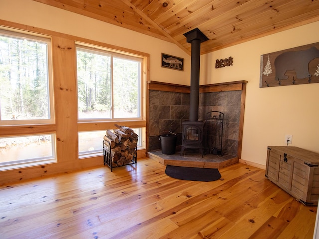 living area with a wood stove, lofted ceiling, hardwood / wood-style flooring, plenty of natural light, and wooden ceiling